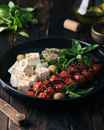 feta cheese and baked cherry tomatoes, basil and olives, salad, selective focusの写真素材