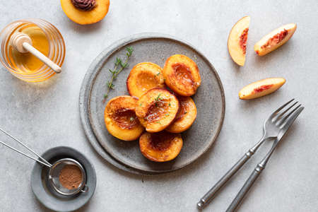 Baked peaches with honey and cinnamon in a ceramic plate, top viewの写真素材