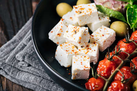 feta cheese and baked cherry tomatoes, basil and olives, salad, selective focus, close-upの写真素材