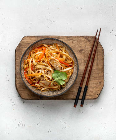 Asian food, wok noodle with vegetables and chicken in ceramic bowl, top viewの写真素材