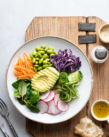 Vegan Buddha bowl with avocado, edamame beans, cucumber, red cabbage, carrots, radishes and spinach....