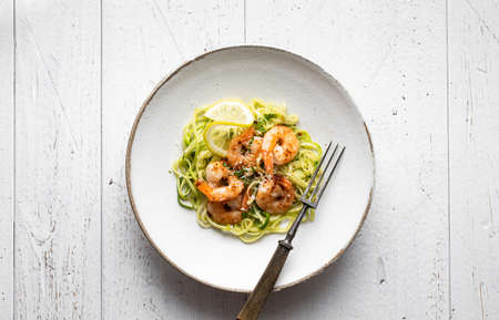 zucchini noodles with shrimps on white wooden background, top view , copy spaceの写真素材