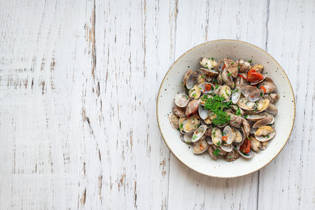 Fresh steamed clams with white wine, garlic and parsley on a white wooden background, top viewの写真素材
