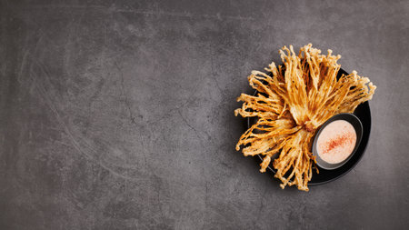 Fried Enoki Mushrooms with sauce on black background, top view, copy spaceの写真素材