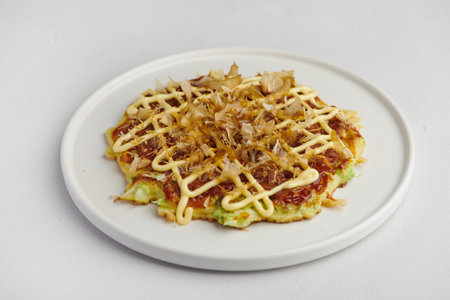 Okonomiyaki with mayo and bonito flakes on white plate, selective focusの写真素材