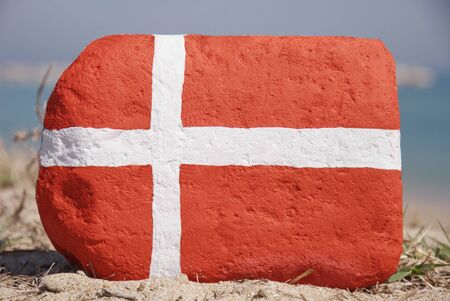 Denmark flag painted over a stone on the sandの写真素材