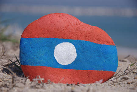 Laos flag painted over a stone on the sandの写真素材