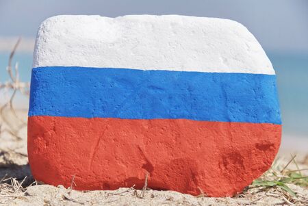 Russia flag painted over a stone over the sandの写真素材
