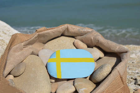 Swedish flag on a stone in a bag with pebblesの写真素材