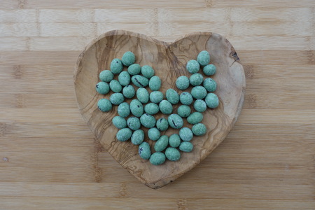 Wasabi Coating Roasted Peanuts on a wooden heart containerの写真素材