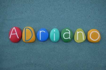 Adriano, latin male name composed with multi colored stone letters over green sandの写真素材