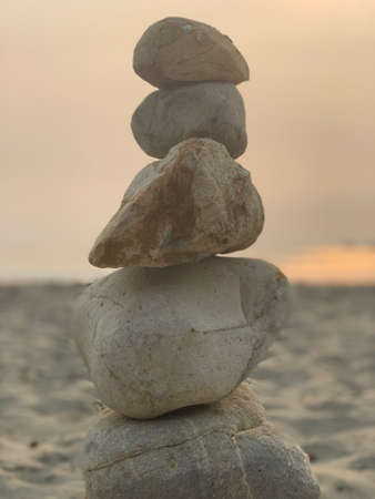 Stones stacked on top one another on beach at sunsetの写真素材