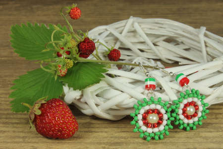 Pair of earrings with strawberry on wooden backgroundの写真素材
