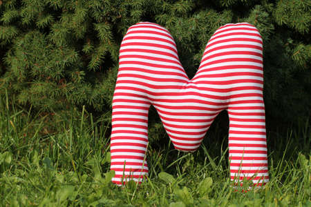 Striped textile letter on sward in the gardenの写真素材