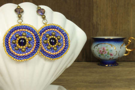 Earrings on white ceramic shell on wooden backgroundの写真素材