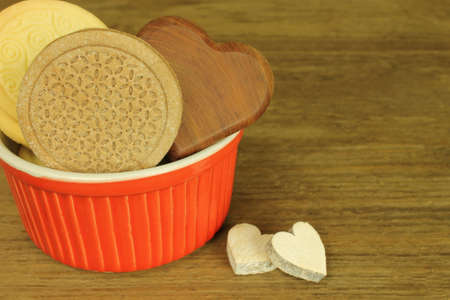 Biscuits in red bowl with wooden heartsの写真素材