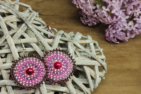 Pair of pink earrings with lilac on wooden backgroundの写真素材