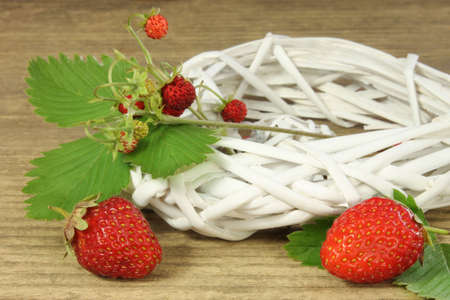 Red strawberries with wicker decoration on wooden backgroundの写真素材