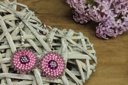 Pair of pink earrings with lilac on wooden backgroundの写真素材