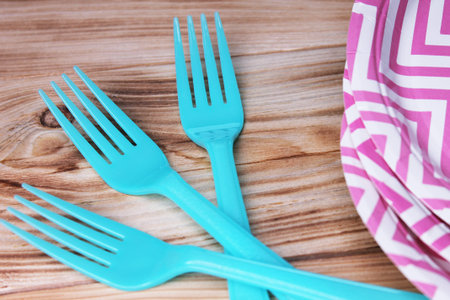 Plastic forks and paper plates in detail on wooden background
