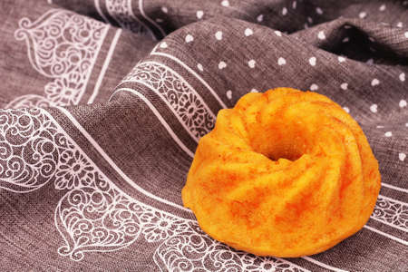 Little carrot cake in detail on grey tablecloth with white patternの写真素材