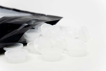 Round disposable fat glue containers made of plastic for eyelash extension treatment on white background.の写真素材