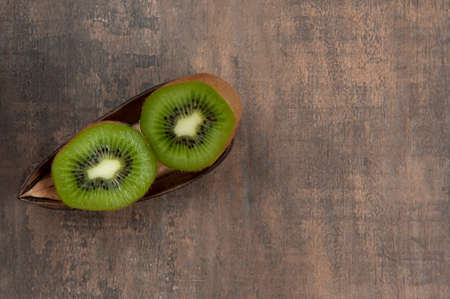 Kiwi fruit, rich in vitamin C, two half. Aged wood color background. Top view. From above. Space for text. Horizontal.の写真素材