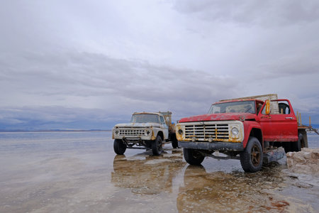 UYUNI, BOLIVIA, JANUARY 31, 2018: Old trucks on reflected surface of Salar de Uyuni salt lake flat,...