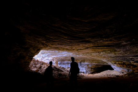 Two unrecognizable tourists at the entrance of Gruta Da Lapa Doce, impressive cave in Iraquara, Chapada Diamantina, Bahia, Brazil, South Americaの写真素材