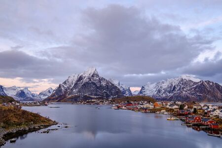 Beautiful view of Reine, with the snow covered mountains in the background and the famous fishing cabins Rorbu in the foreground, Lofoten Islands, Moskenesoya, Nordland, Norway, Europeの写真素材