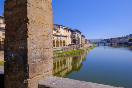 Florence, Tuscany, Italy, March 30, 2019: Written messages or love letters on a pillar of the famous Ponte Vecchio, the Old Bridge and city houses with reflections in the Arno River, Florence, Italyのeditorial素材