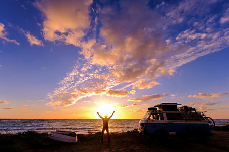 Unrecognizable vanlifer with his old vintage van by the sea and enjoys the sunset, Lazio, Italy