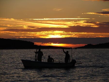 Angleres in small boat on sunset         の写真素材