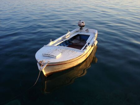 wodden boat anchored on dark calm sea           の写真素材