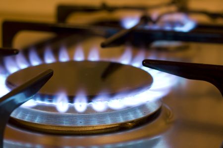 Flame on gas stove under orange lightの写真素材