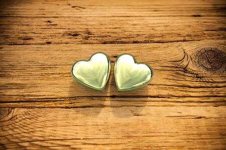 3D rendering of two golden hearts on old wooden backgroundの写真素材