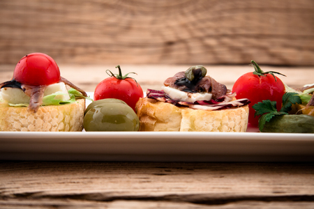 Crostini vith mozzarella cheese anchowy and tomato on wooden boardの写真素材