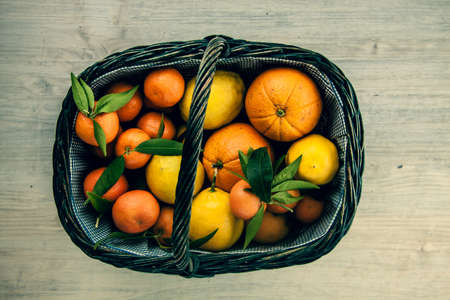 Various fresh citrus fruits in basket on old wooden backgroundの写真素材