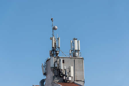 Mobile data and communication antenna on the building roof front of the blue skyの写真素材