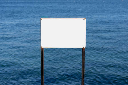 During sunny bright day time blank white board in front of the blue seaの写真素材