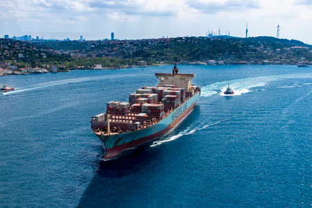 Huge cargo ship passing under the bridge during the sunny summer day. Large cargo ship transporting intercontinental industrial goodsのeditorial素材