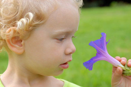 Eco friendly blondie girl staring at violet flowerの写真素材