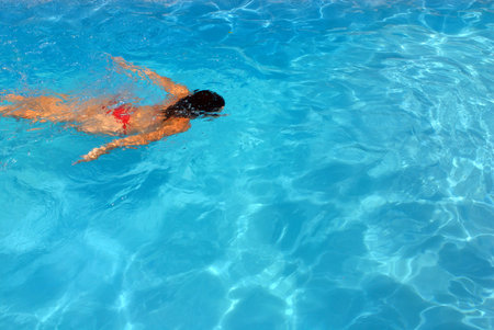 Girl swimming underwater in a clear water swimming pool