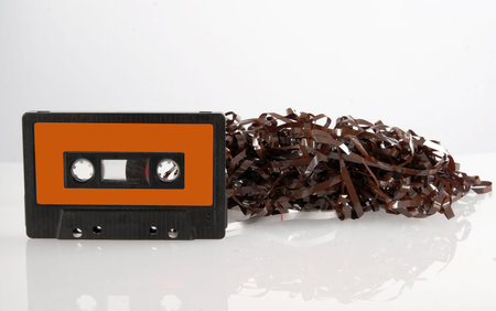Single black audio cassette and tangled tape isolated with its reflection  on white background....