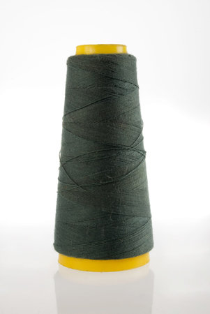 A bobbin of dark green thread isolated with its reflection on white background. Included clipping...