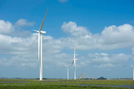 Renewable energy farm multiple wind mills on field and blue sky background. Includes clipping path, so you can easily cut and place on a design.の写真素材