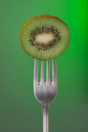 Kiwi fruit on fork over color background, concept photo. Ideal for healthy eating campaign or fitness poster.の写真素材