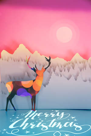 Merry christmas handmade paper cut winter scene in pop art style: deer with bokeh lights and forest landscape on sunset sky background. Ideal for holiday greeting card, xmas poster or campaign.の写真素材