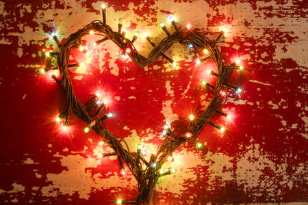 Holiday concept, love composition with heart shape made from christmas lights on grunge wood texture background.の写真素材