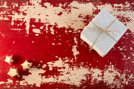 Holiday greeting card concept background, top view vintage gift box and paper gold stars on grunge red wood texture.の写真素材